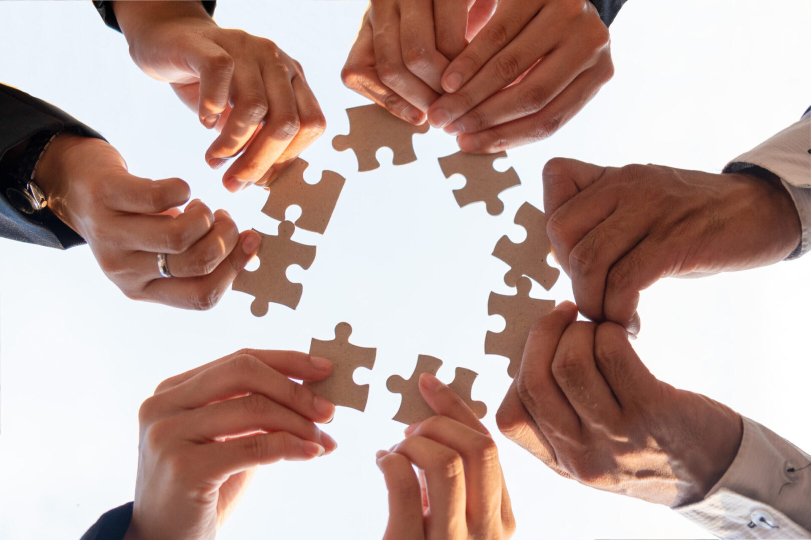 The hand of a businessman holding a paper jigsaw And solving the puzzle together. The business team assembles a jigsaw puzzle. A business group wishing to bring together the puzzle pieces